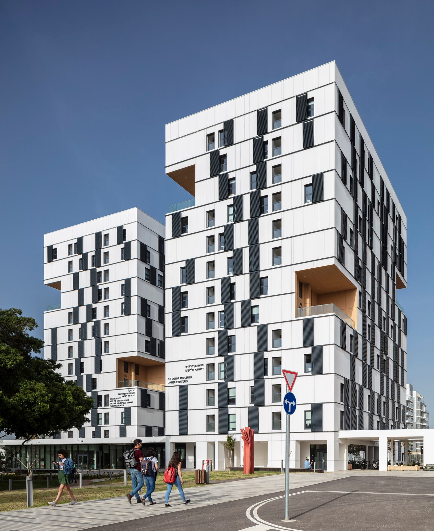 The Daphna and Gerald Cramer Dormitories tower at Reichman University, with students walking past