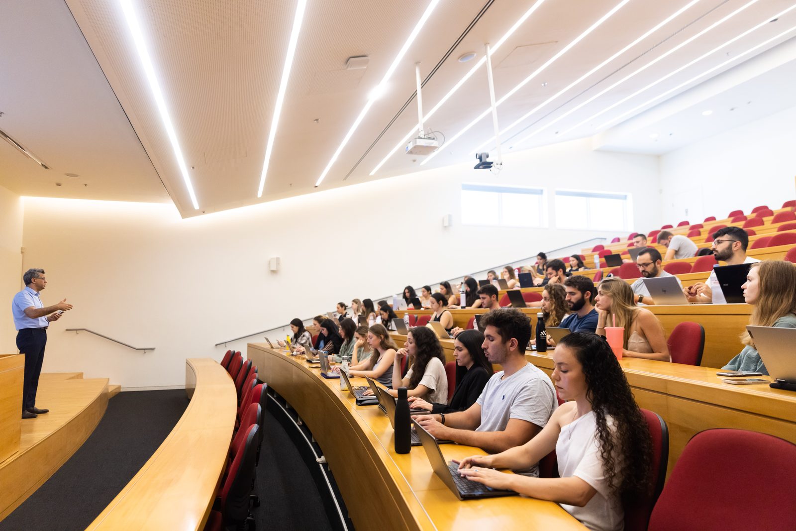A professor teaching a class of students in a tiered lecture hall at Reichman University
