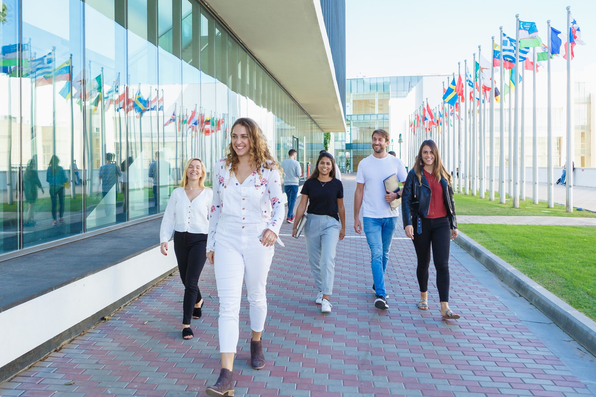 Students walking a campus path at Reichman University, lined with the flags of many nations