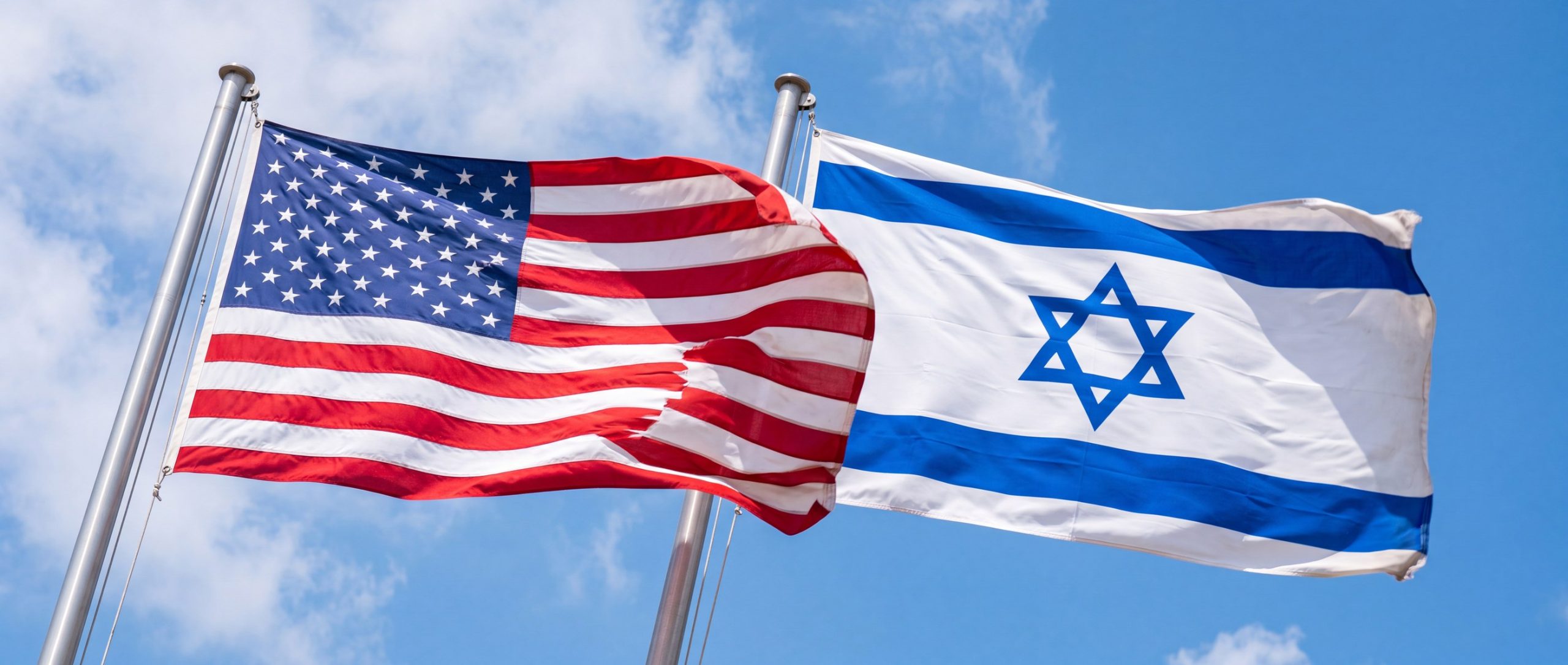 The United States and Israeli flags waving together against a bright blue sky
